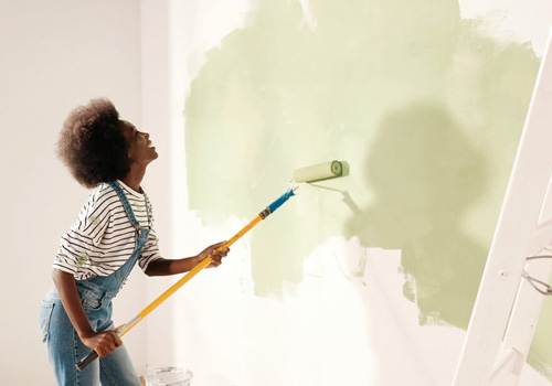 young women renovating her home and painting her walls x