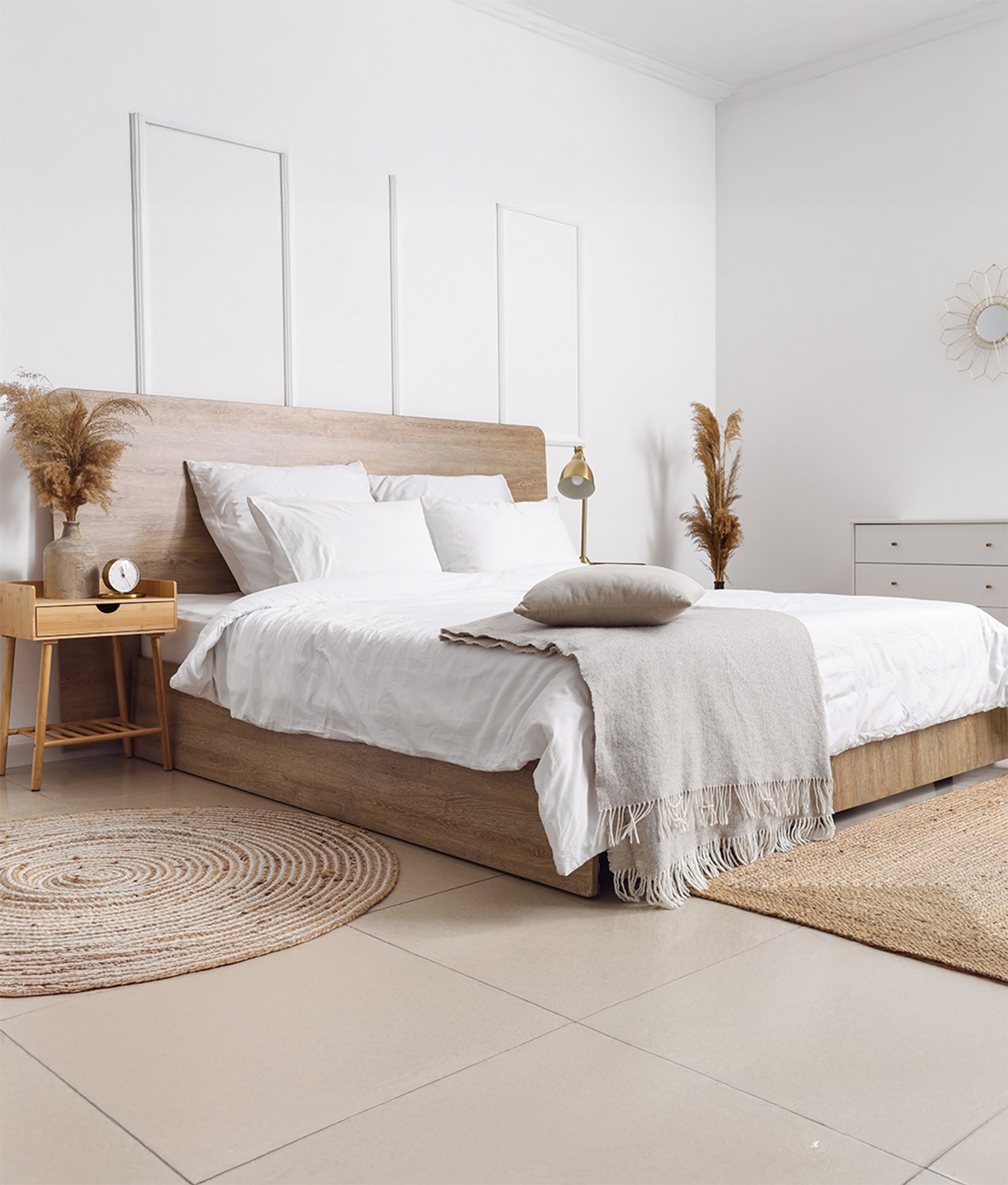 Comfortable bed dry reeds and chest of drawers near white wall