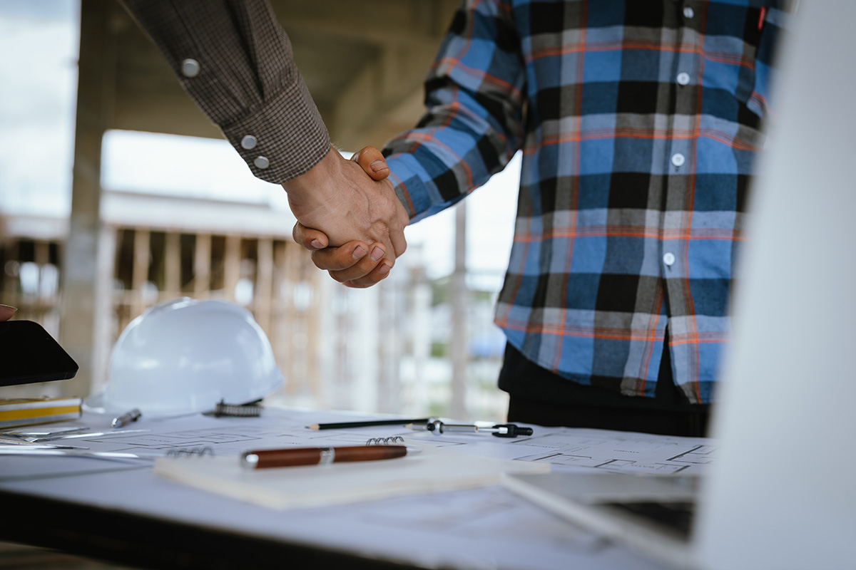 client shaking hands with agent on blueprints and design